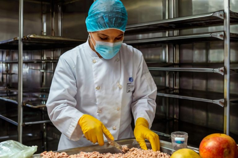 Operario en planta de producción alimentaria procesando productos en línea industrial